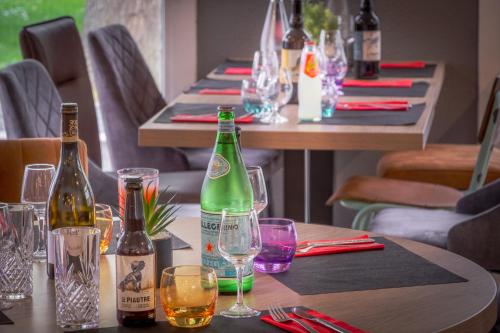 a table with wine bottles and glasses on it at The Originals City, Angers Sud, Le Village 49 in Les Ponts-de-Cé