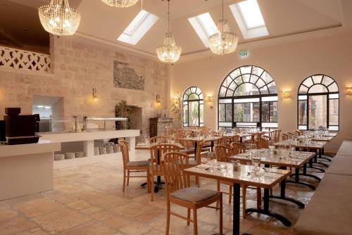 a dining room with tables and chairs and windows at Gloria Hotel in Jerusalem