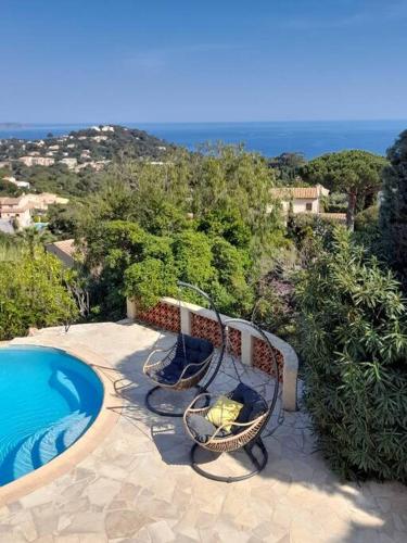 a patio with two chairs and a swimming pool at 4-Star Private Villa with Heated Pool and Panoramic Sea View at Gulf de Saint Tropez in Cavalaire-sur-Mer