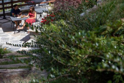 two people sitting at a table in a garden at La Cascata Chambres d'hôtes in La Salle