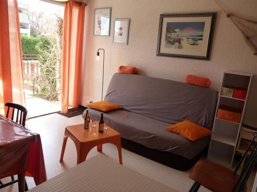 un salon avec un canapé et une table dans l'établissement Sol-y-Days Yucca, Agreable appartement en RDC avec petite terrasse et parking à 150m de la plage, au Grau-du-Roi