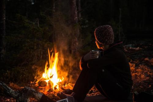 a man sitting in front of a fire at Vålådalens Fjällstation in Vålådalen