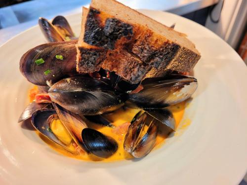 a plate of food with mussels and a piece of bread at St Tudy Inn in Bodmin