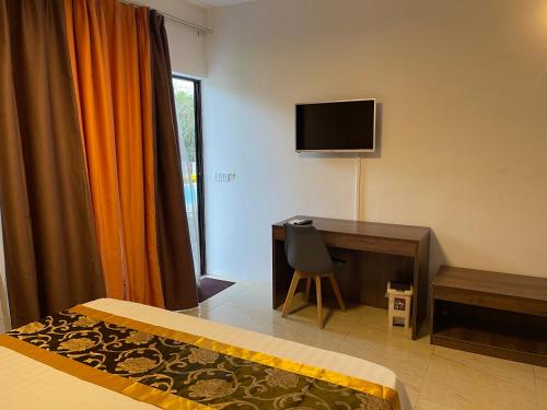 a hotel room with a desk and a television at Welcome Inn in Grand Baie