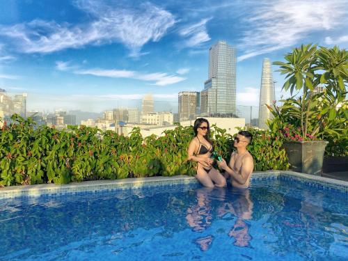 a man and a woman sitting in a swimming pool at Adora Art Hotel in Ho Chi Minh City