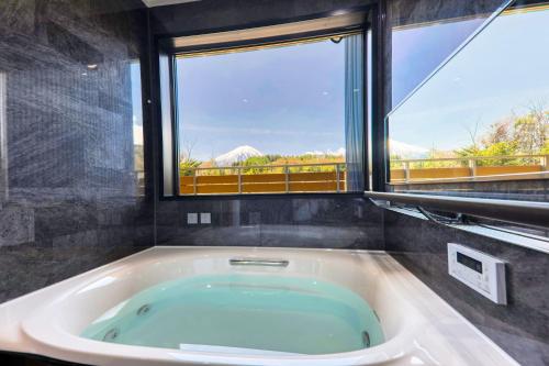 un bagno con una grande vasca e una grande finestra di Glamping Cottage Kawaguchiko a Fujikawaguchiko