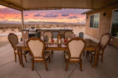 een houten tafel en stoelen op een patio met uitzicht op de woestijn bij CASA DE SUNSET-JTNP -The Ultimate Desert Getaway in Twentynine Palms