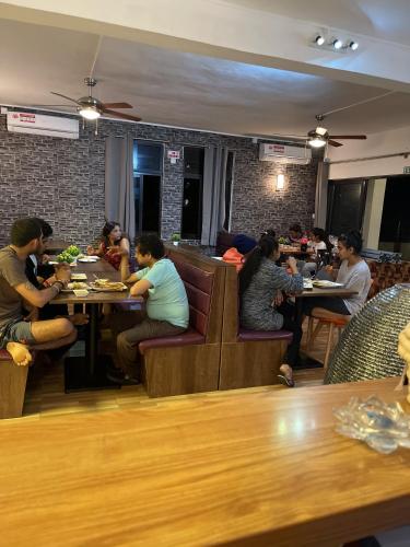 a group of people sitting at tables in a restaurant at Welcome Inn in Grand Baie