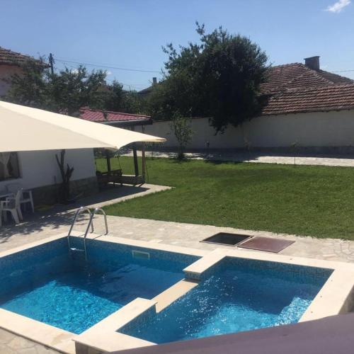 a swimming pool in a yard with an umbrella at Вила Вълнара in Sredets