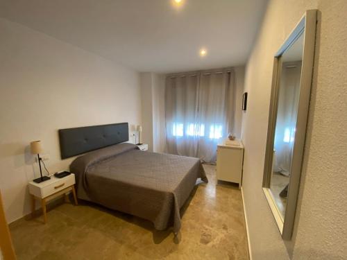 a small bedroom with a bed and a mirror at Apartamento Tía Maria in Cádiz