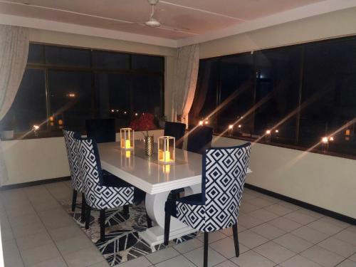 uma mesa e cadeiras num quarto com janelas em Penthouse 42 at Ezulweni em Amanzimtoti