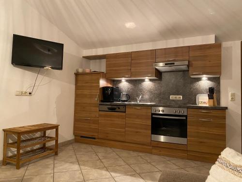 a kitchen with wooden cabinets and a tv on the wall at Sepps Appartement in Fieberbrunn