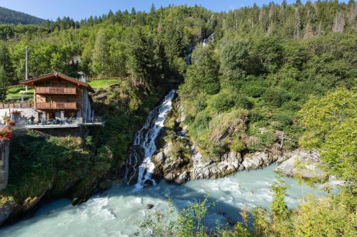 a house on the side of a river with a waterfall at La Cascata Chambres d'hôtes in La Salle