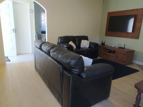 sala de estar con sofá de cuero y TV en Casa aconchegante com lareira en Campos do Jordão