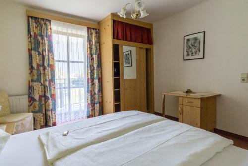 Un dormitorio con una gran cama blanca y una ventana. en Pension Mitterer, en Weissensee