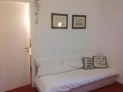 a white couch in a room with two pictures on the wall at Voglia di mare in Capraia