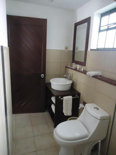 a bathroom with a toilet and a sink and a mirror at Mara River Lodge in Aitong