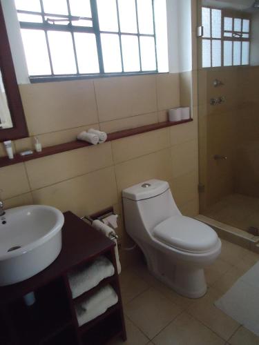 a bathroom with a white toilet and a sink at Mara River Lodge in Aitong
