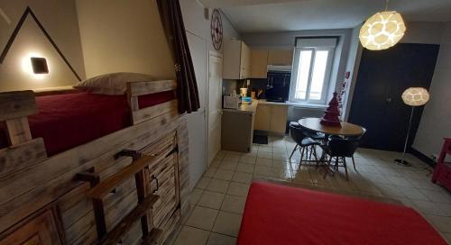 1 dormitorio con cama, mesa y cocina en Un petit studio à la montagne, en Ax-les-Thermes