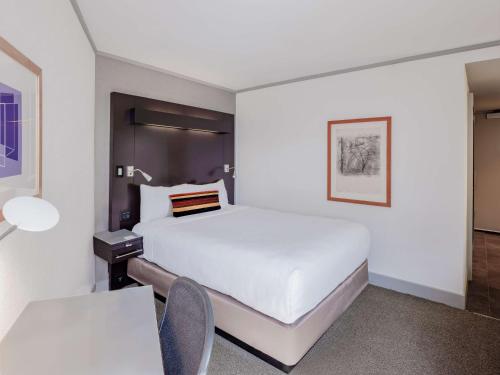 a bedroom with a white bed and a table and chairs at The Royal Sonesta Boston in Cambridge