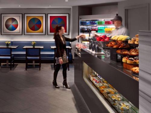 a woman is standing behind the counter of a bakery at The Royal Sonesta Boston in Cambridge