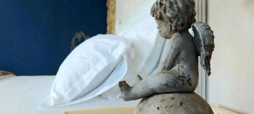 a statue of a little girl sitting next to a bed at maison d'hôtes Le Courty in Blousson-Sérian