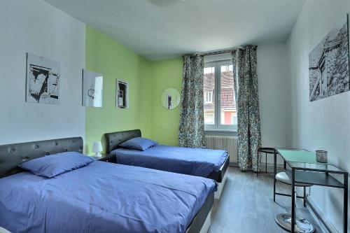 a bedroom with two beds and a table and a window at "Urbaine Colors" Appartement coloré et lumineux "Les Péri-Urbaines" in Riedisheim