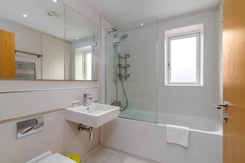 a bathroom with a sink and a shower and a mirror at GuestReady - Bright & Modern Flat in Southwark in London