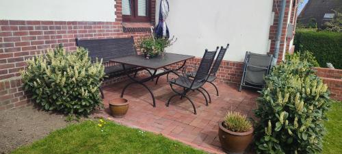 a patio with a table and chairs and some plants at Ankerplatz, Am Hafen Ost 10 in Carolinensiel