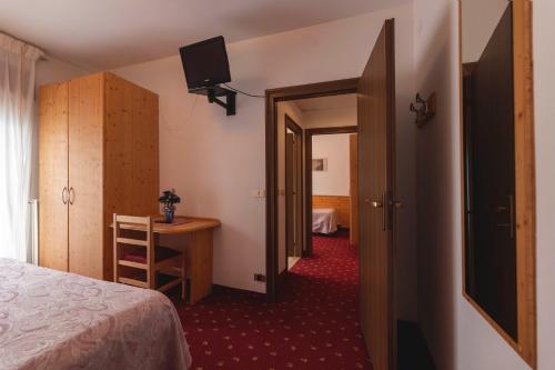 a bedroom with a bed and a desk and a television at Hotel Castel Mani in San Lorenzo in Banale