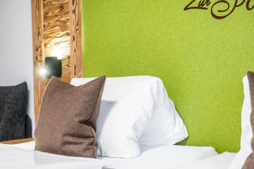 a green bedroom with a white bed with a pillow at AlpinSpa zur Post - Bergbahn im Sommer 2025 inklusive in Bad Gastein