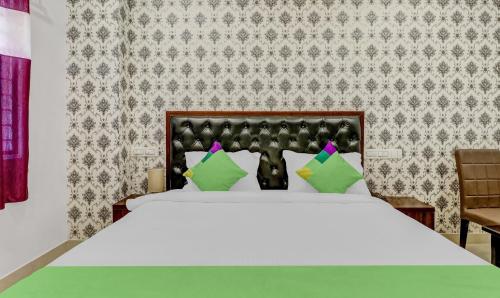 a bedroom with a large white bed with green pillows at Treebo Three Drops in Bengaluru