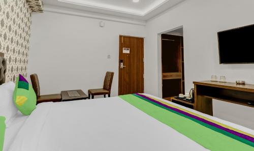 a bedroom with a bed and a desk and a television at Treebo Three Drops in Bengaluru