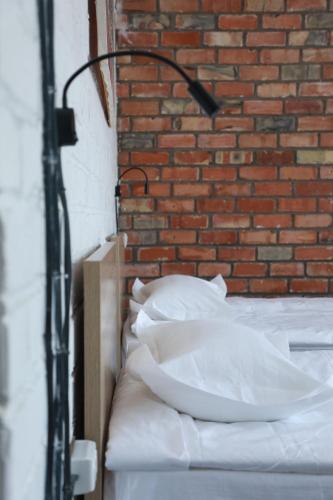 a bed with white pillows in front of a brick wall at Olive Ala-Archa Hotel & SPA in Verkhnyaya Alaarcha