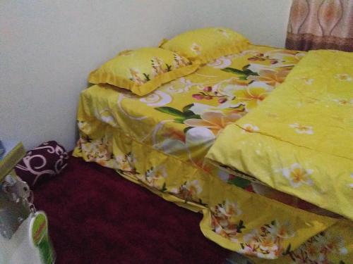 a bedroom with a bed with a yellow comforter at Zahra Syariah Home Stay in Bukittinggi