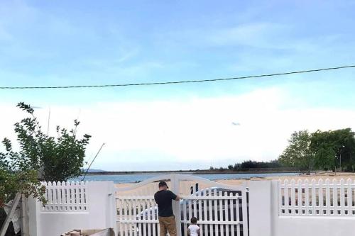 a man and a child standing next to a white fence at Sea Kecil Tiny House near Jetty of Kuala Besut in Kampong Nail