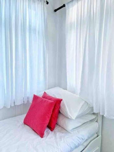 a white bed with two red pillows on it at Sea Kecil Tiny House near Jetty of Kuala Besut in Kampong Nail