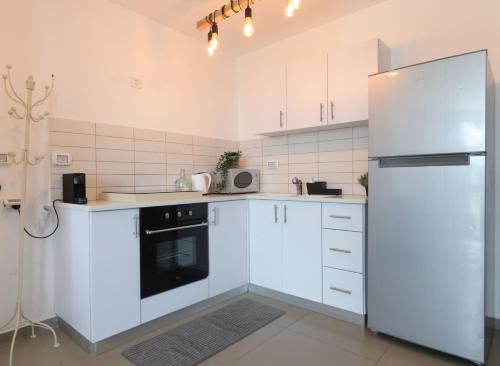 a kitchen with white cabinets and a refrigerator at YalaRent Migdalor Apartments with Sea Views Tiberias in Tiberias