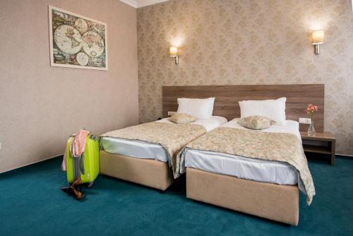 a hotel room with two beds and a suitcase at Hotel Alkor in Truskavets