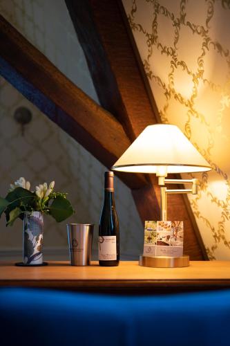 a bottle of wine and a lamp on a table at Boutiquehotel Kloster Pfalzel in Trier