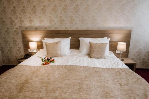 a large white bed with a bouquet of flowers on it at Hotel Alkor in Truskavets