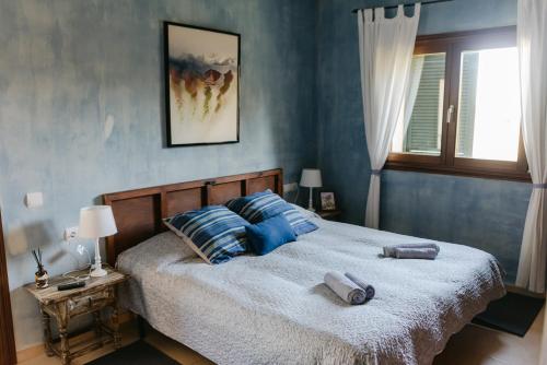 a bedroom with a bed with blue walls and a window at Villa Beatrice in Sencelles