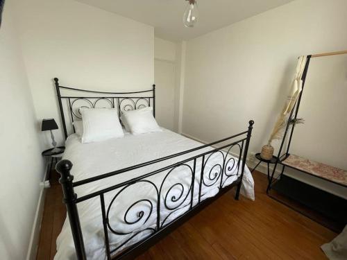a bedroom with a black bed with white pillows at Les Petites Fécampoises by Mathilde in Fécamp