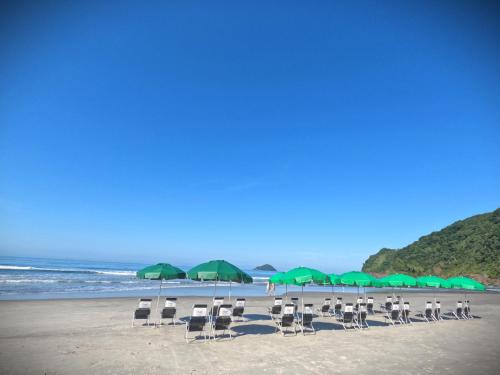 a beach with chairs and green umbrellas and the ocean at Pousada Villa Atlântica in Camburi