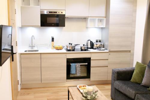 a kitchen with a stove top oven next to a couch at Lovely Studio Apartment with access for Wheel-chairs in Sydenham in Forest Hill