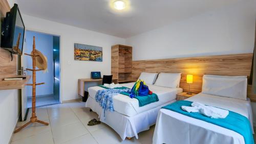 a hotel room with two beds and a television at Hotel Refugio in Maceió