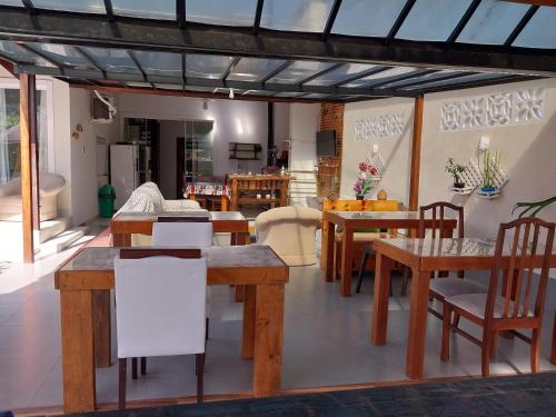 comedor con mesas y sillas de madera en Pousada Cantinho da Tia Sandra- suite 7, en São Francisco do Sul