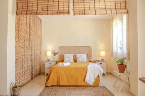 um quarto com uma cama e duas mesas de cabeceira e duas janelas em MonKeys Apartments Sanlúcar Beach Relax em Sanlúcar de Barrameda