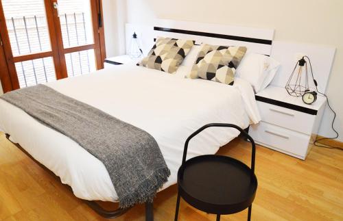 1 dormitorio con 1 cama blanca grande con silla negra en Apartamento Encanto Tarazona Plaza de España en Tarazona de Aragón