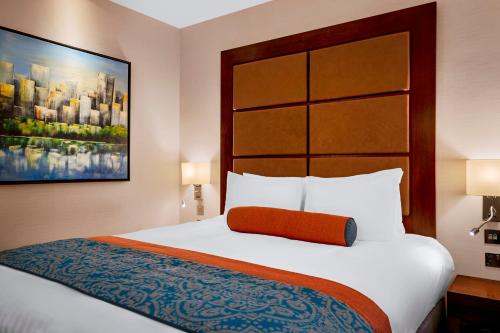 a hotel room with a large bed with a orange pillow at Leonardo Royal London St Paul’s in London